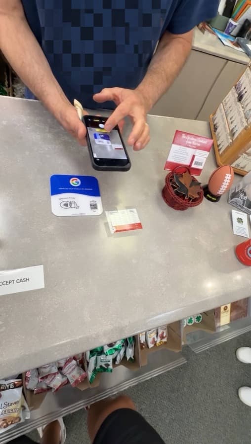 A Google review card on a shop counter, tapped with a phone (1)