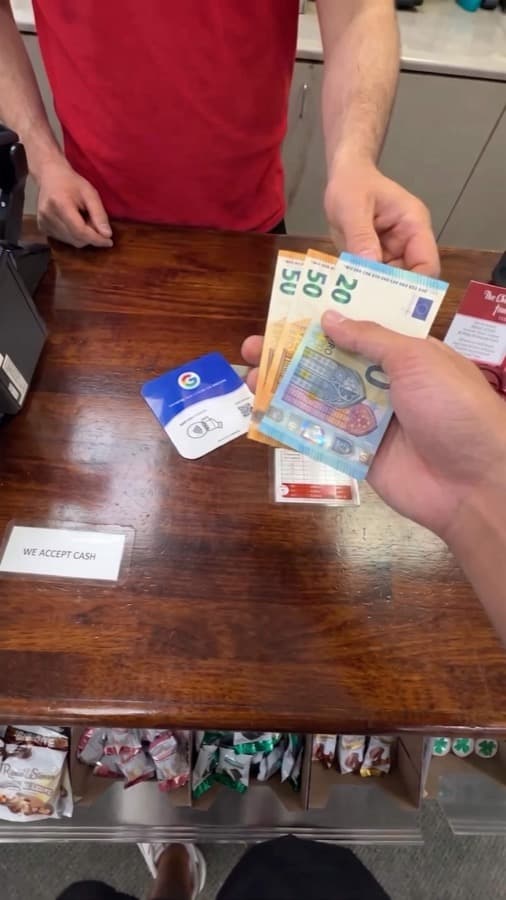 A Google review card on a shop counter, tapped with a phone (2)